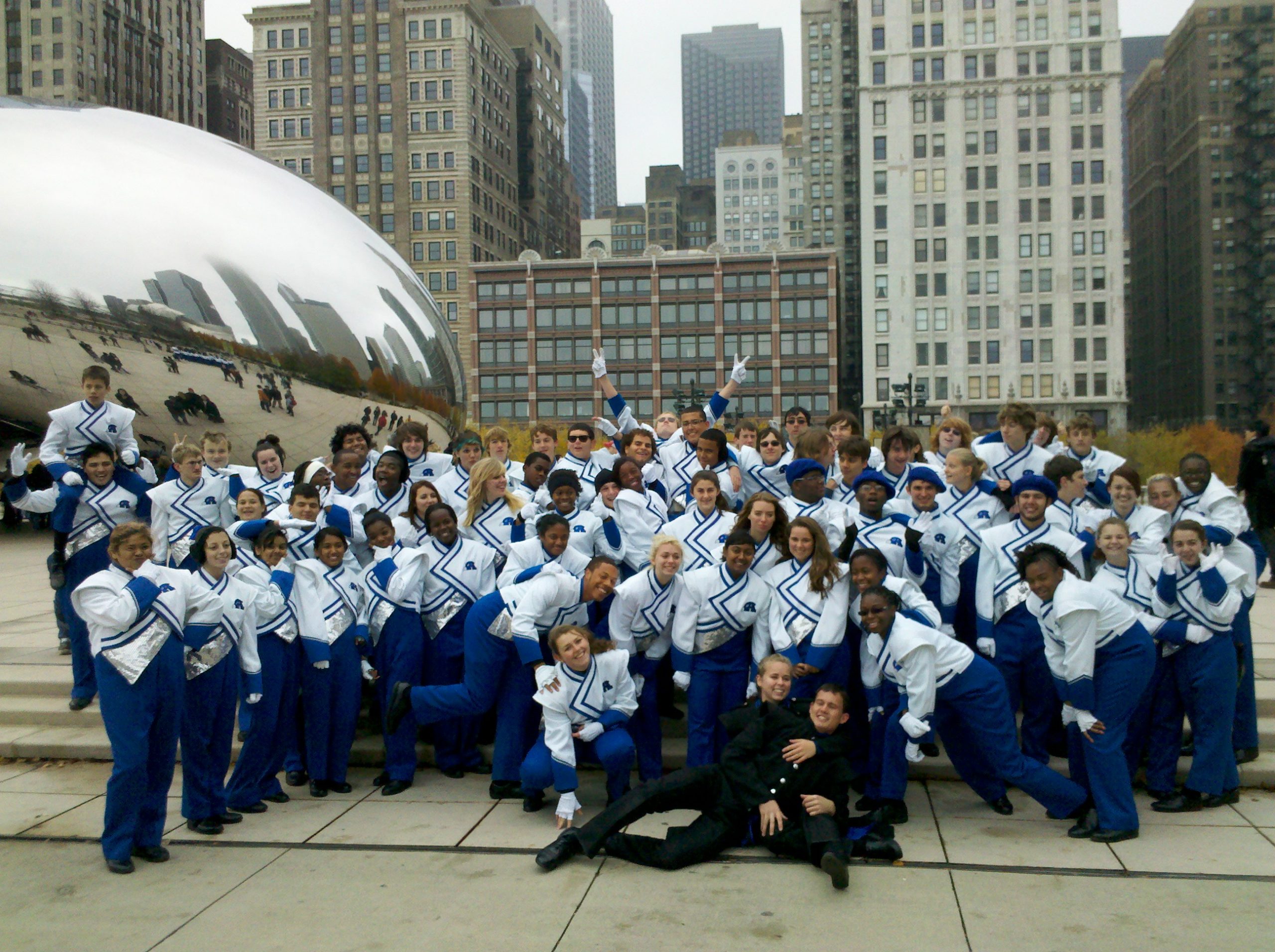 Group of middle school students dressed in matching marching band uniforms posing in front of The Bean in Chicago City