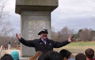 Educational tour guide giving a speech to students in front of Gary Old North Bridge in Concord, MA