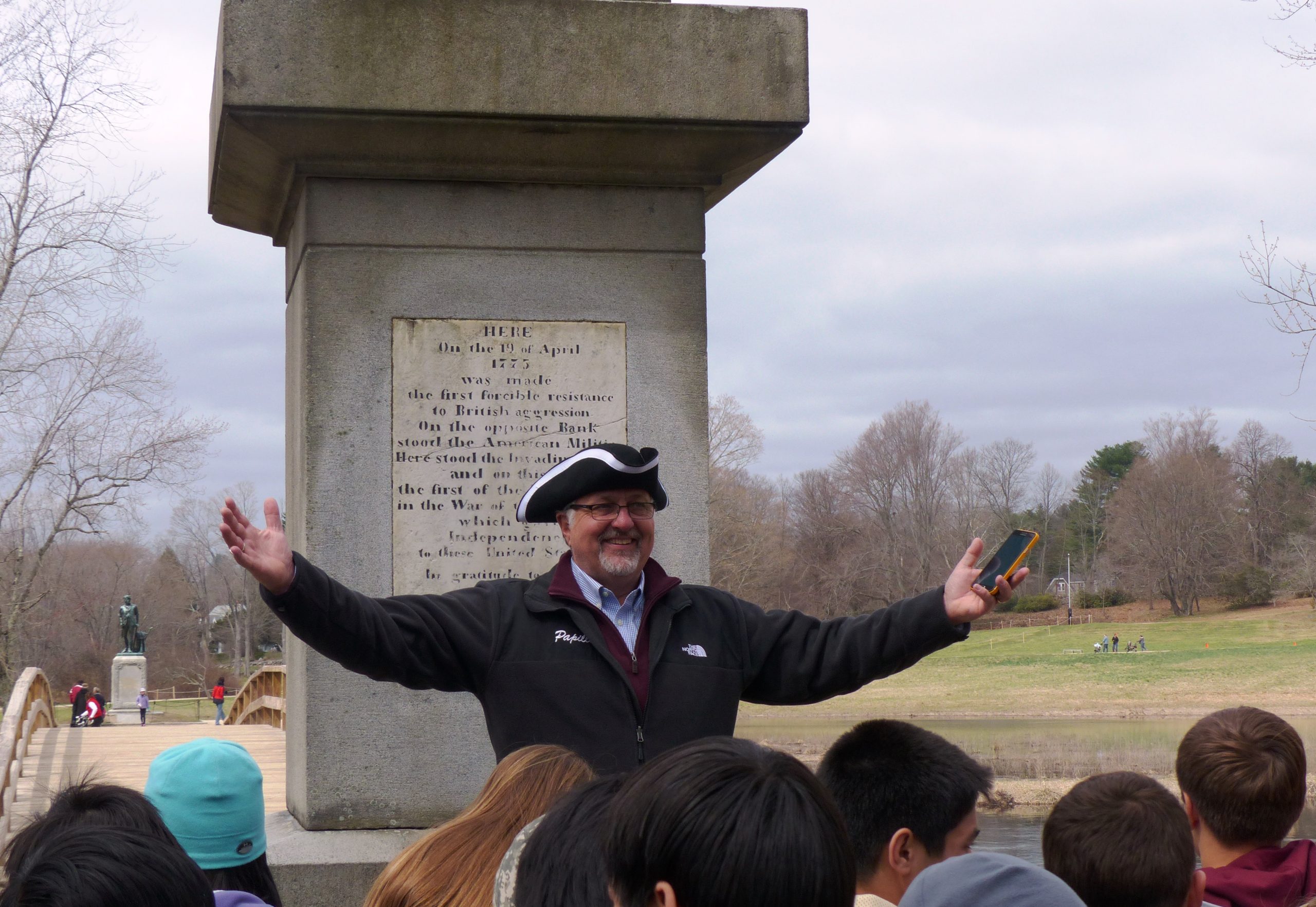 Educational tour guide giving a speech to students in front of Gary Old North Bridge in Concord, MA