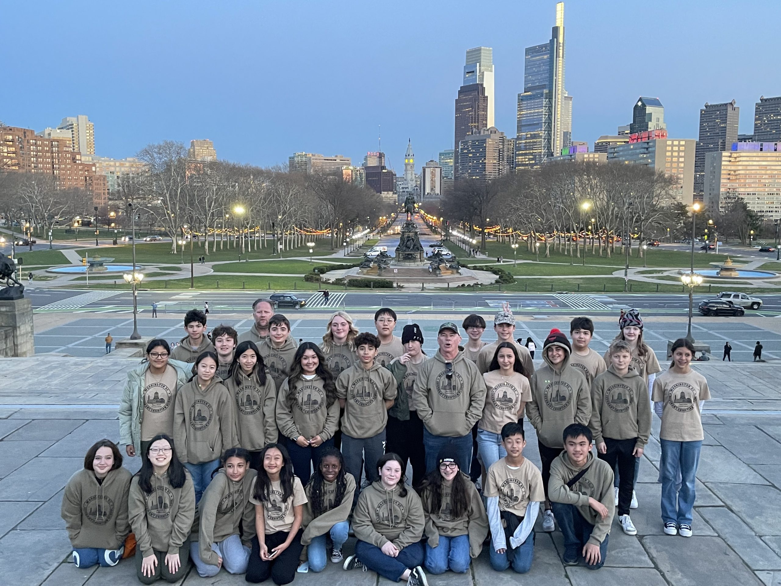 Group of middle school students posing in Philadelphia PA, with a cityscape in the background