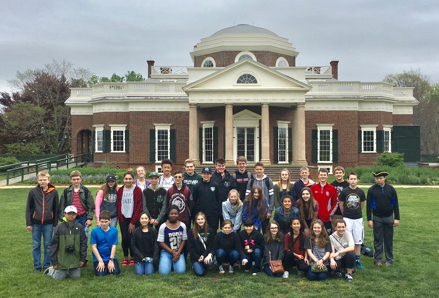 Group of middle school students posing in front of historical American building