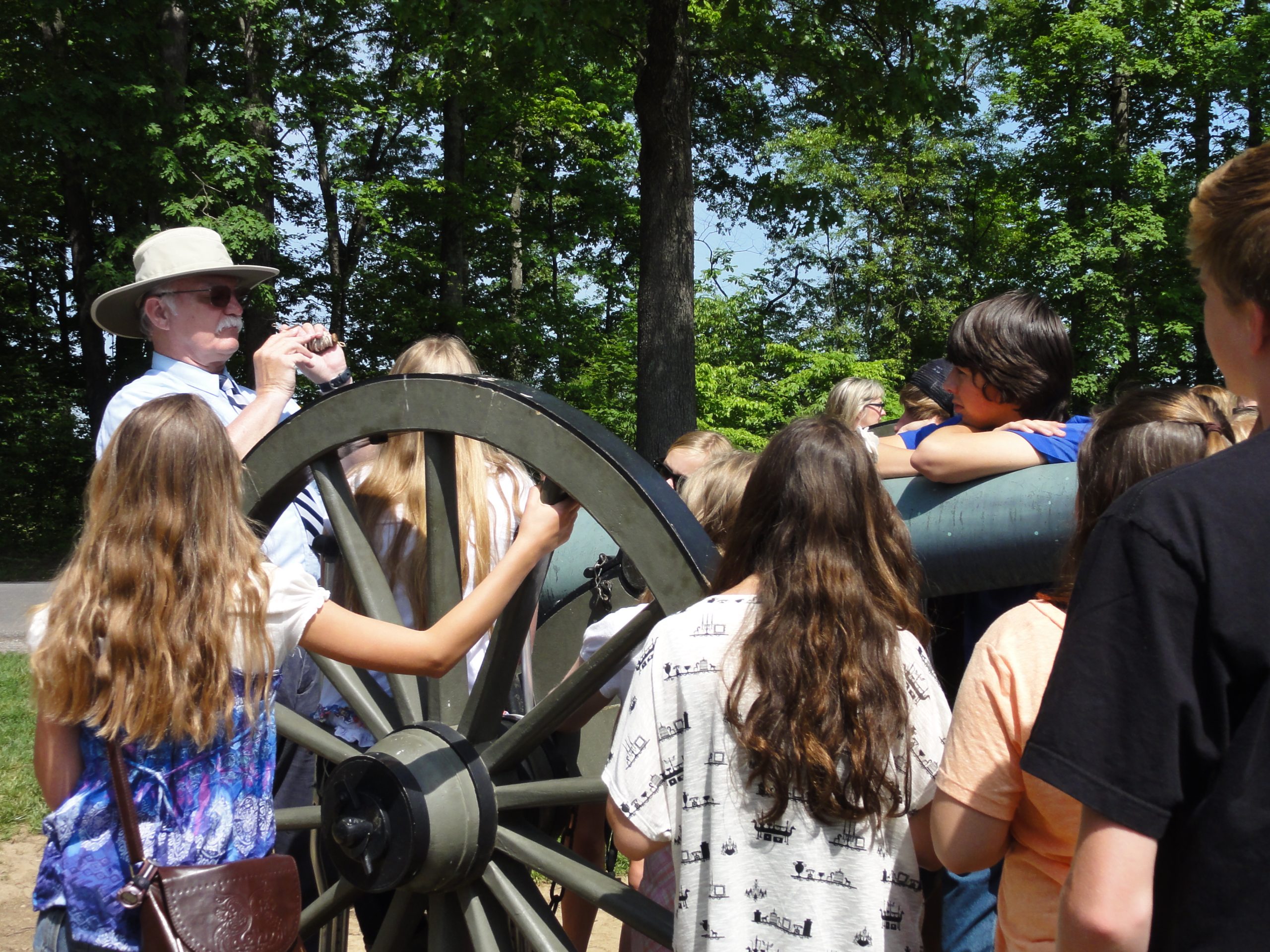 Middle school students standing around a civil war canon listing to an educational tour guide