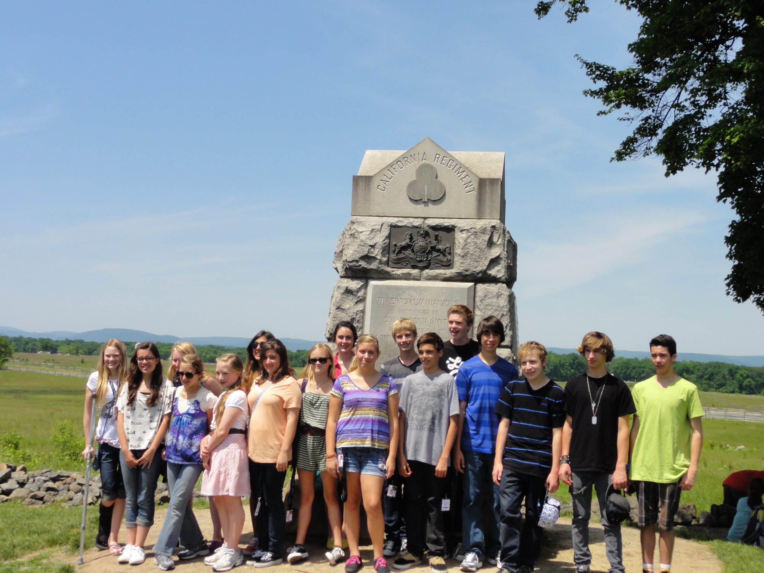 Group of middle school students standing in front of California Regiment monument in field