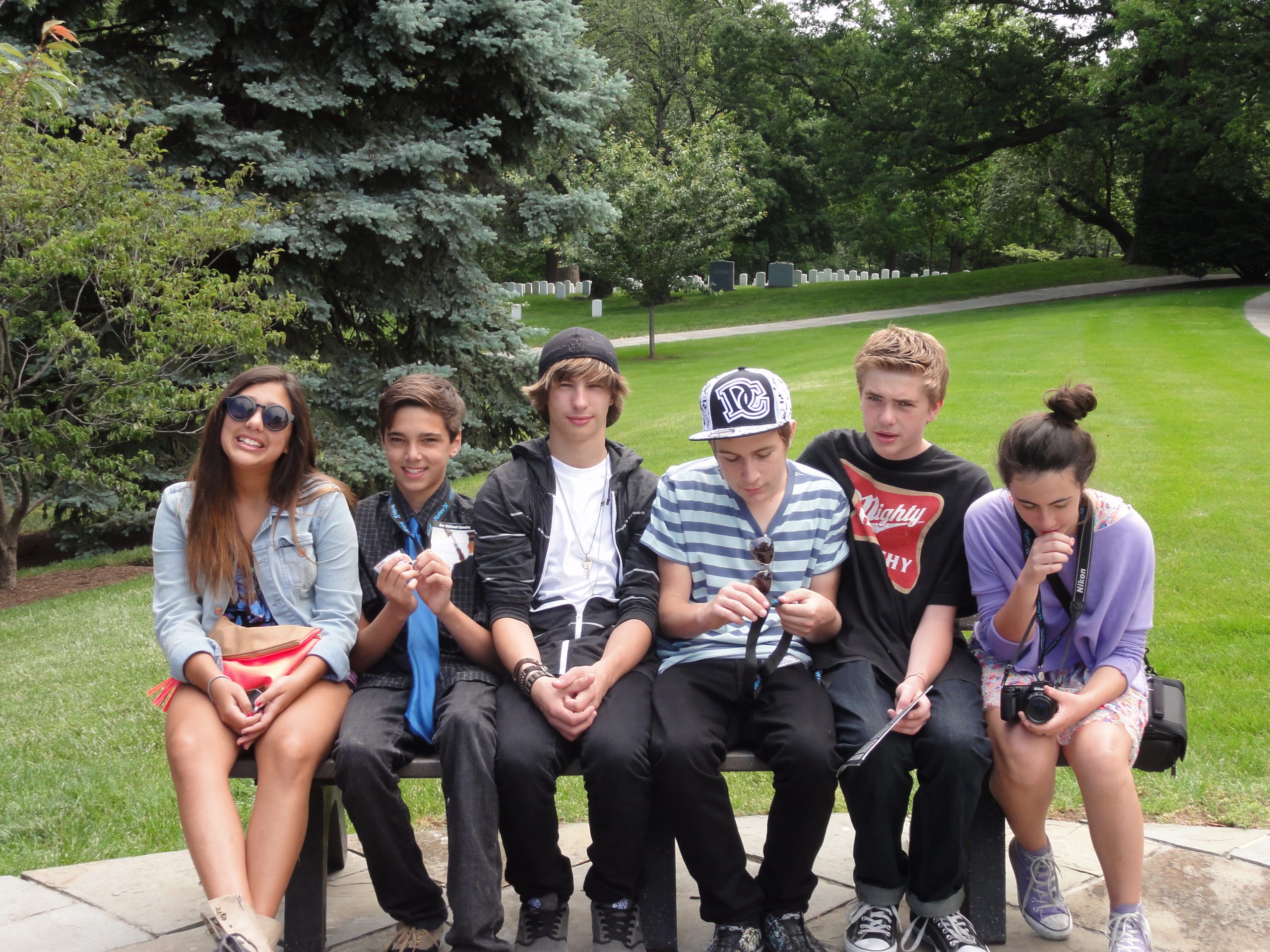Six teenage boys and girls sitting on a bench in Arlington War Memorial Park