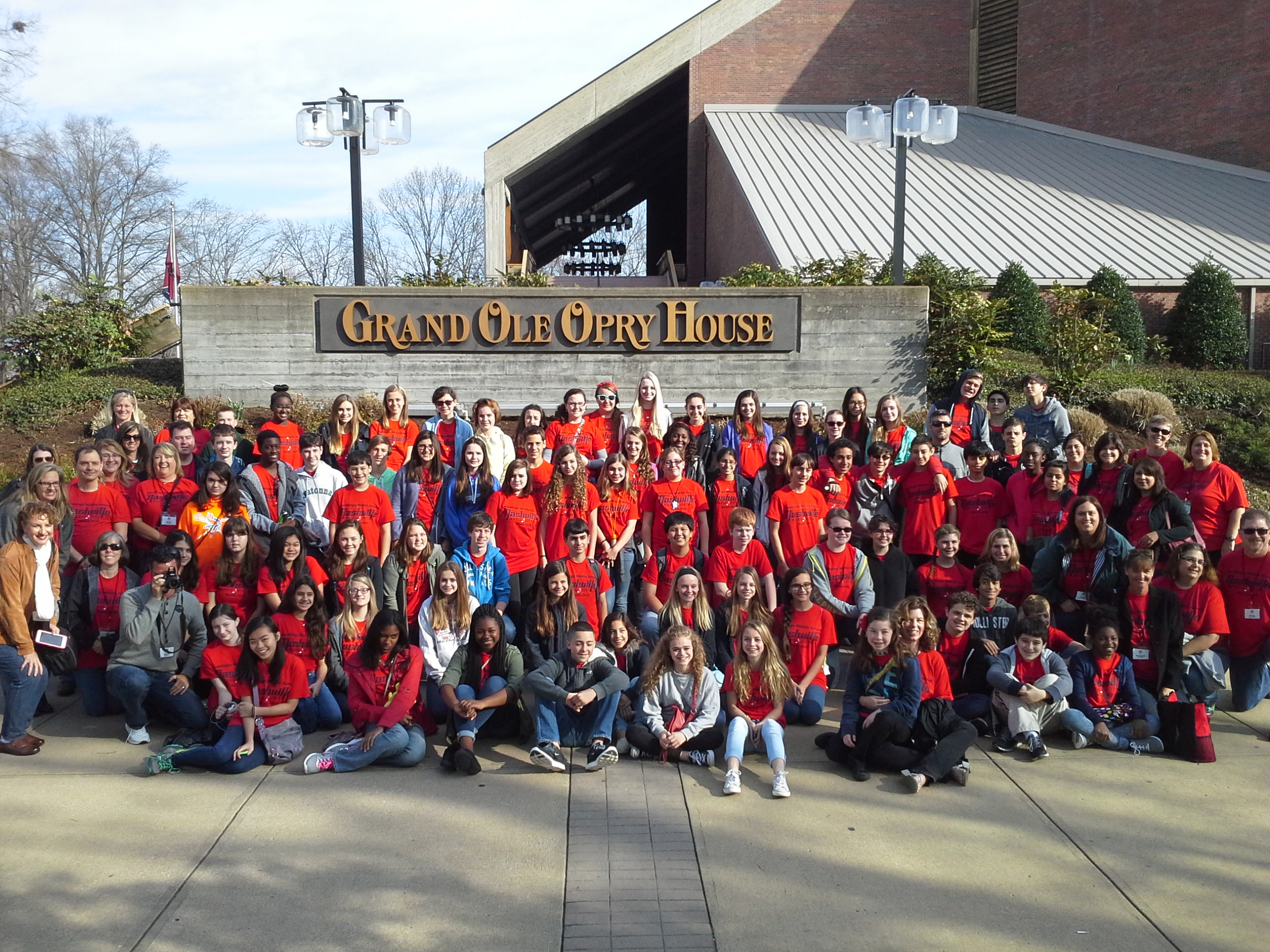 Group of high school students in red shirts standing in front of Grand Ole Opry House Sign