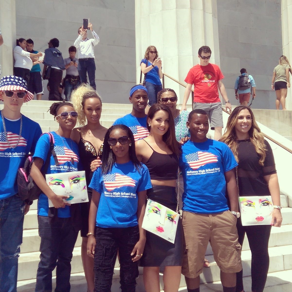 Group of high school students with matching American flag shirts standing on steps of national building in Washington DC